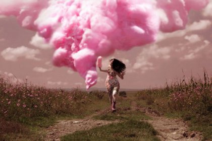 Girl running in a field in front of a pink cloud