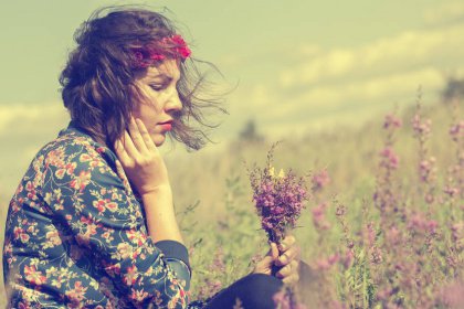 Meisje zit in een veld met een boeket wilde bloemen