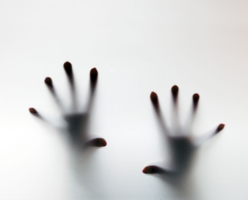 Two hands on the other side of a translucent wall