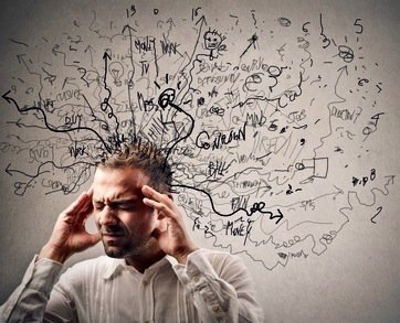 A man with eyes closed holding his head as crazy thoughts escape