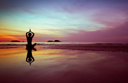 Beach at sunset, silhouette of figure meditating