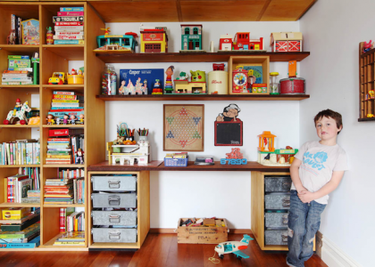 Boy in his room next to tall his toys 
