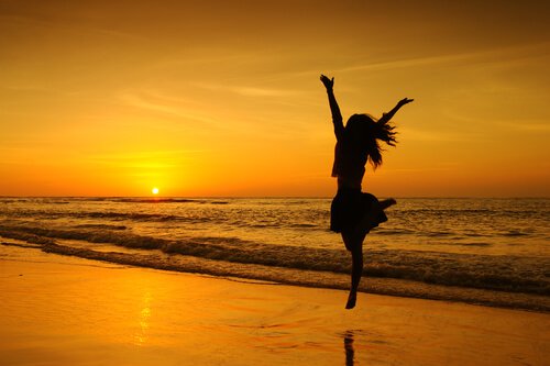 girl jumping on beach in sunset single 