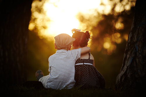 boy sitting hugging a girl at sundown