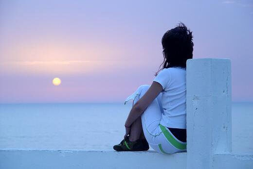 Vrouw aan zee kijkt naar zonsondergang