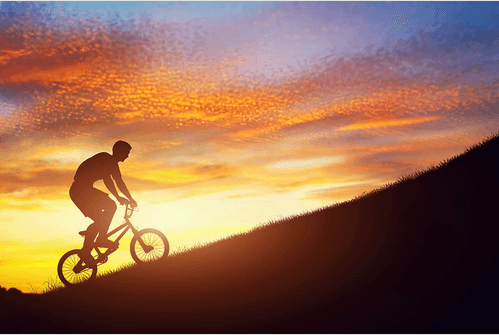 motivated man riding a bike up a mountain