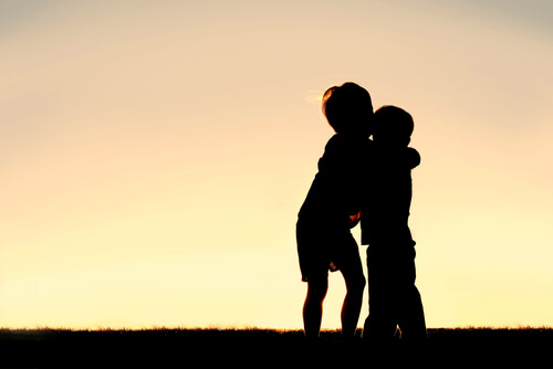 older brother hugging little brother sunset