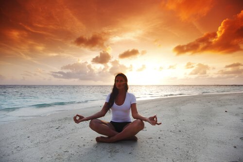 woman in lotus position on the beach meditating