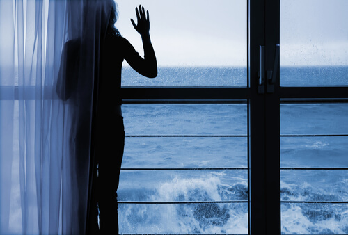 Vrouw kijkt naar zee uit raam