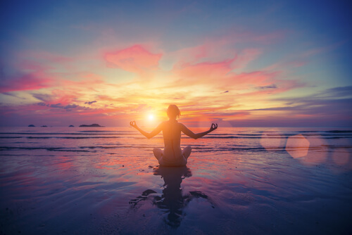 Kvinne mediterer i solnedgangen