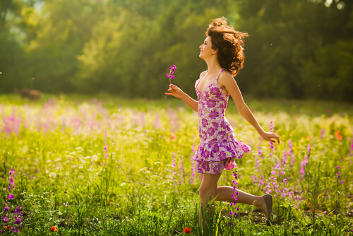 woman walking in flowers smiling and happy