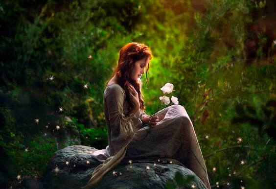 woman in the forest holding a flower