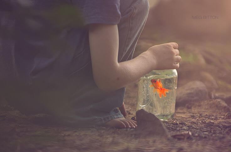 boy covering a glass jar with a fish