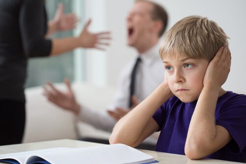 boy covering his ear listening to his parents