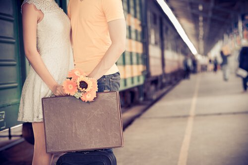 couple holding suitcase train station