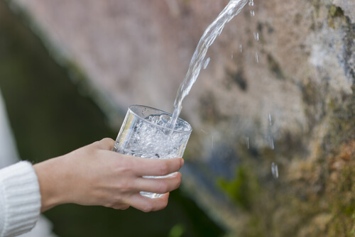 hand holding a glass filling it with water