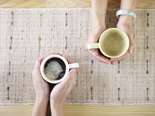 Two People Holding Cups of Coffee