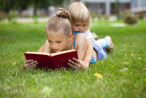 Siblings Reading Together on Grass