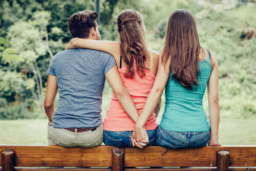 Man Holding Girl's Hand Behind Girlfriend's Back