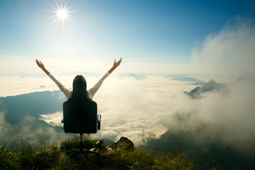Kvinne har et lykkelig liv der hun sitter i en stol på toppen av et fjell