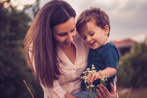 woman-holding-her-child-while-they-look-at-a-flower