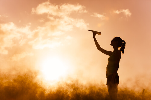 girl throwing paper airplane