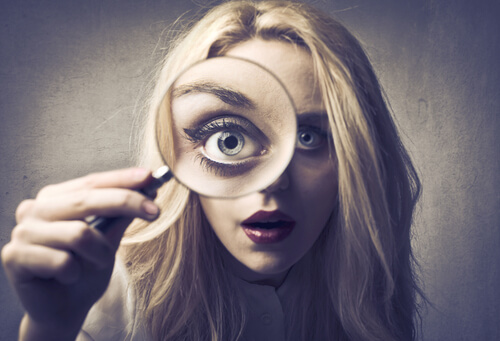 Being too self-critical: a woman looking through a magnifying glass.