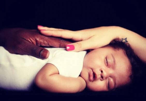 two-hands-of-color-stroking-a-baby