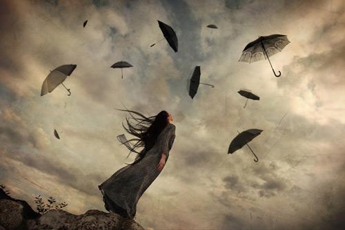 woman-looking-at-umbrellas-flying-in-the-wind
