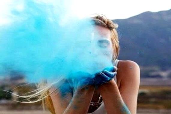 girl blowing blue dust