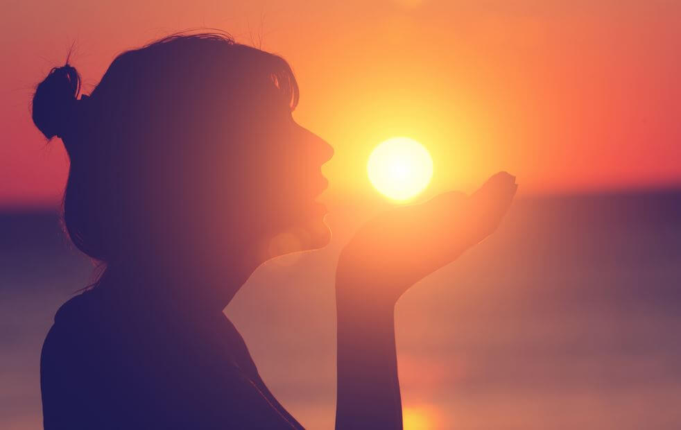 silhouette of girl holding sun at sunset