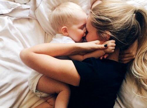 mom playing with baby in bed