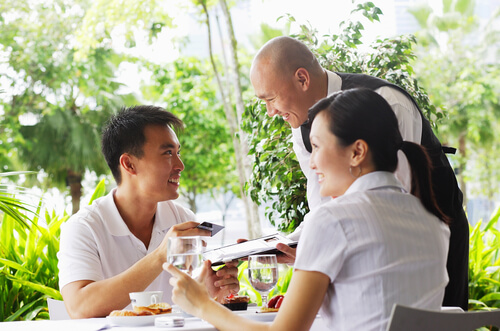 An Asian couple paying their restaurant bill.