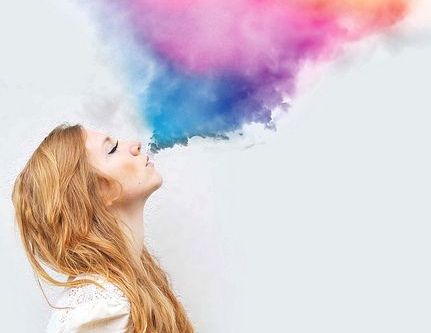 girl blowing out colorful smoke