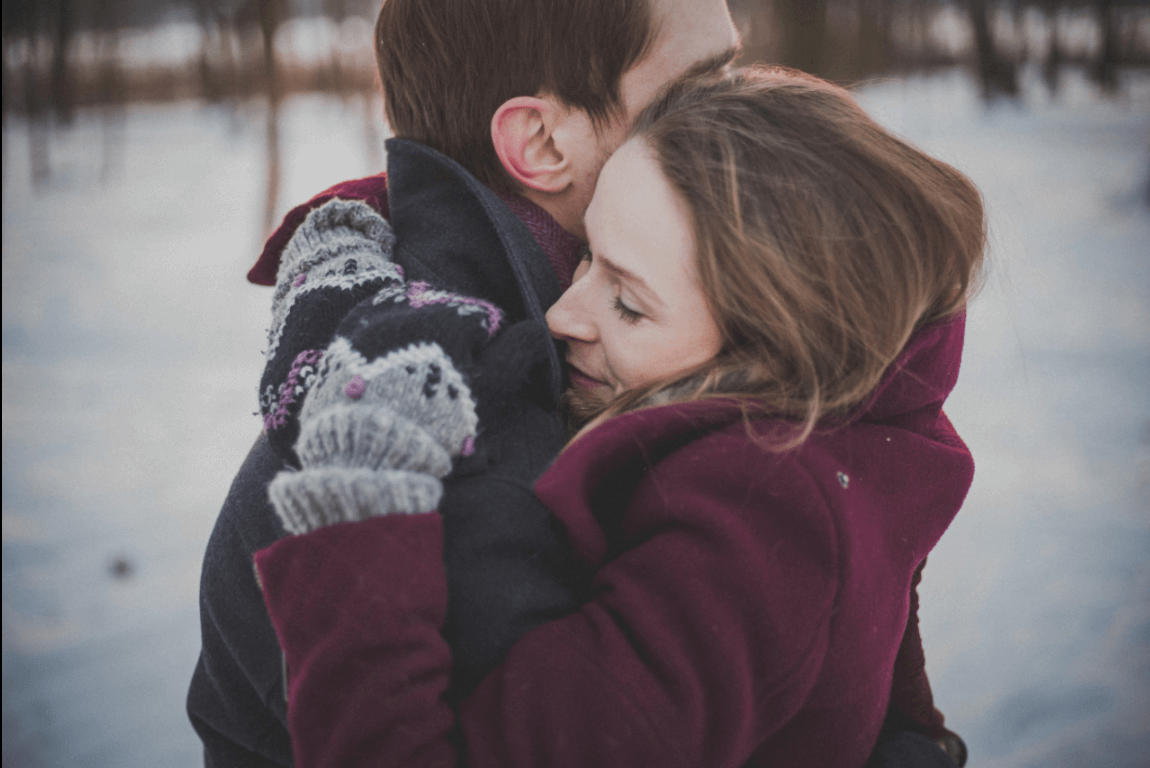 A happy couple in a hug in a snowy field.