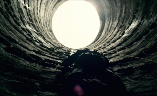 man crawling out of well