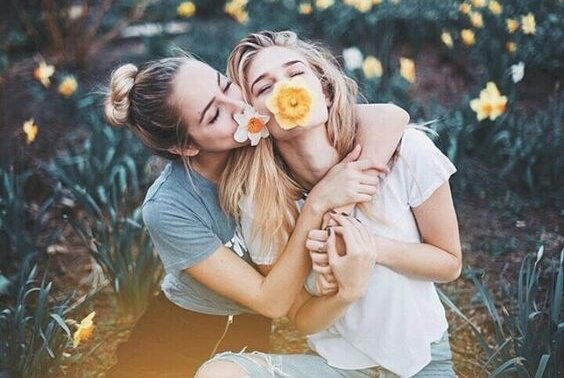 two girlfriends with flowers in their mouths