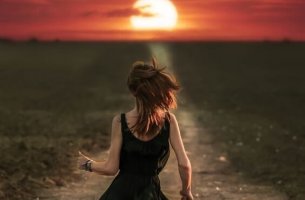 A girl is running towards the sunset.