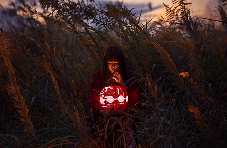 A Japanese girl with a lantern in a field.