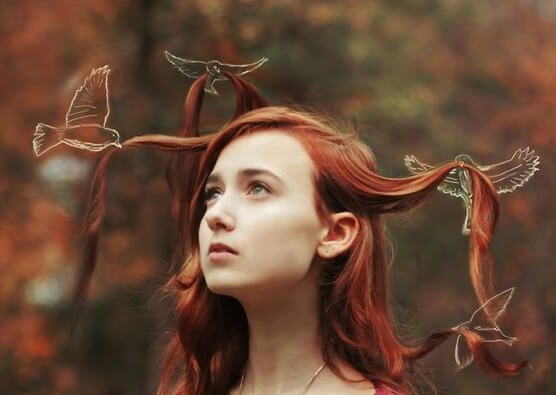 a girl with red hair being held up by white birds