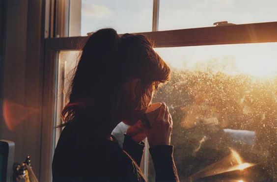 a woman looking out the window with coffee