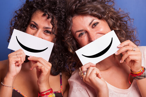 two women holding up smiles to their faces