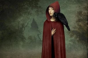 A woman stands in a red hood with a crow on her shoulder.