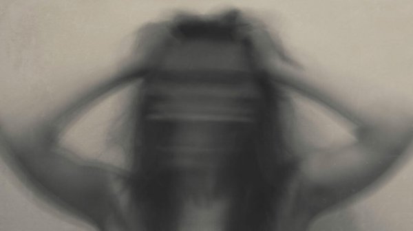a blurry woman with her hands to her head in anxiety
