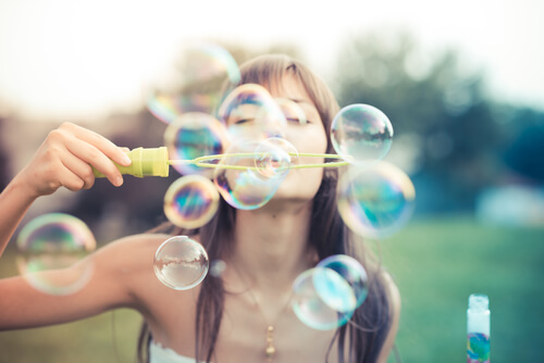 a happy woman blowing bubbles