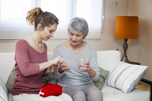 caregiving: a woman taking care of her elderly mother helping with medication
