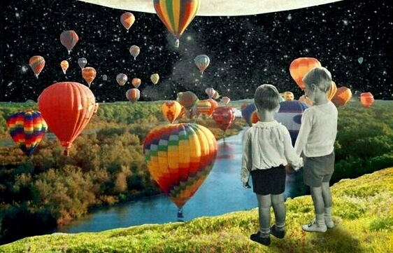 two kids holding hands watching hot air balloons