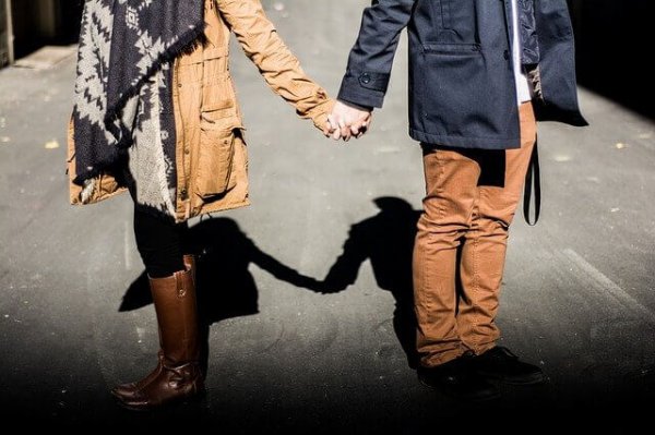 a couple facing away from each other yet holding hands