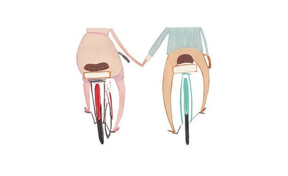 a couple riding bikes, holding hands