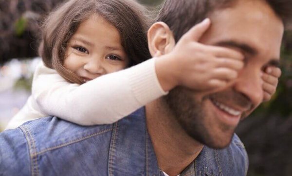A father giving his young daughter a piggy-back ride.